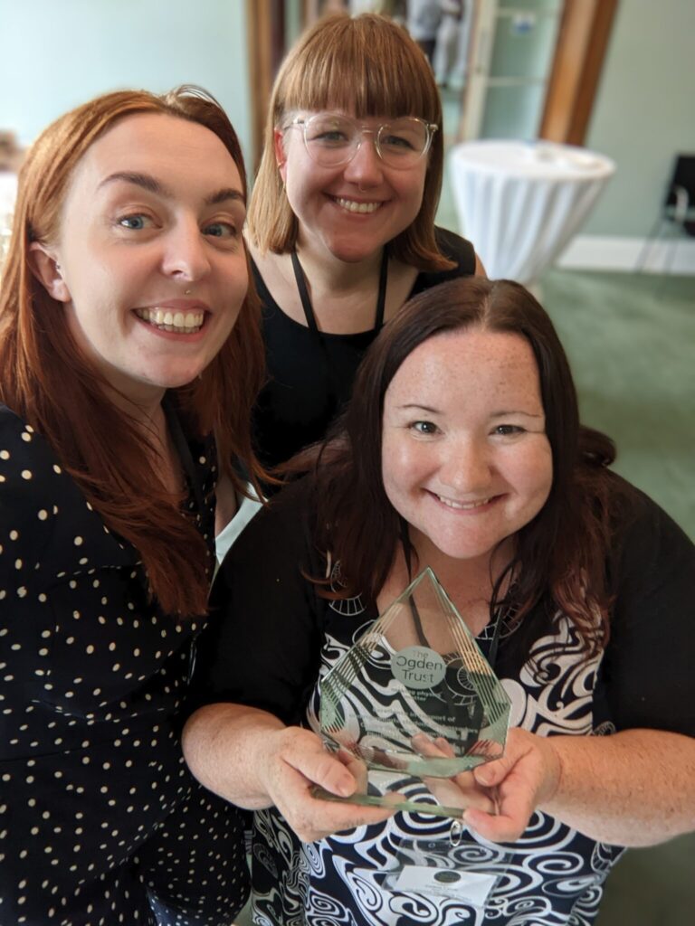 The physics mentoring team holding up the award and smiling